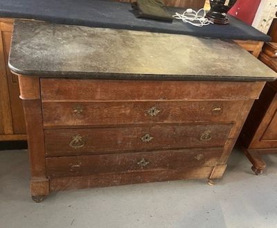 une vieille commode au plateau noir dans une pièce