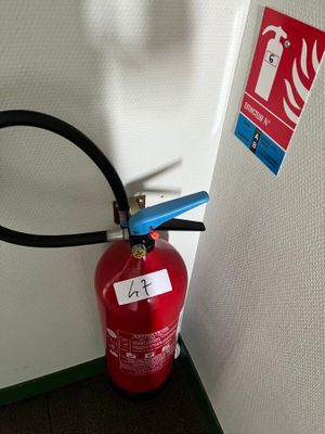 un extincteur fixé au mur à côté d'une borne d'incendie