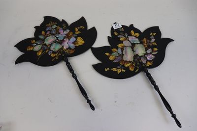 deux épingles à cheveux noires ornées de fleurs et de feuilles, posées sur une table
