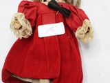 une petite poupée avec une robe rouge et un chapeau rouge