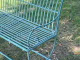 un banc en métal vert posé dans l'herbe du parc