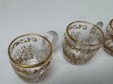 three glass cups with gold designs on them sitting on a table