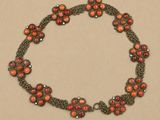 un gros plan d'un collier composé de perles rouges sur fond marron