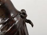 a bronze statue of a woman holding a bird on her shoulder
