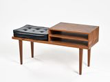 un petit banc en bois sur lequel est posé un pouf noir