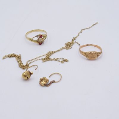 trois bagues en or, un collier et une bague posés sur un fond blanc