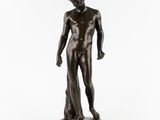 une statue en bronze représentant un homme debout sur un socle