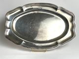 an antique silver plate with a scalloped edge on a white surface