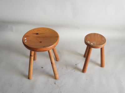 deux petits tabourets en bois placés l'un à côté de l'autre sur une surface blanche