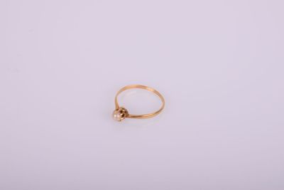 une bague en or ornée d'une perle au centre