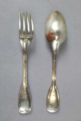 two silver spoons and a fork on a table