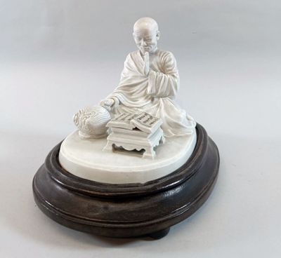 a white statue of a man sitting on a table