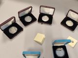a lot of silver coins in small cases on a table