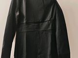une robe en cuir noir suspendue à un cintre devant un mur blanc