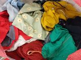 a basket full of clothes sitting on a bed