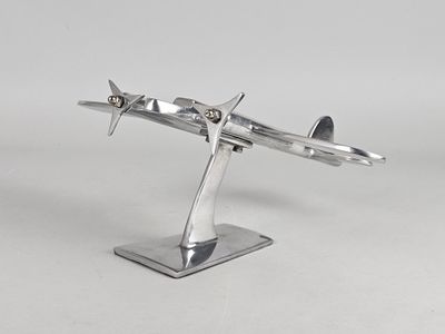 maquette métallique argentée d'un avion posée sur un socle, sur une surface blanche