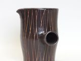 a brown vase that is sitting on a white surface