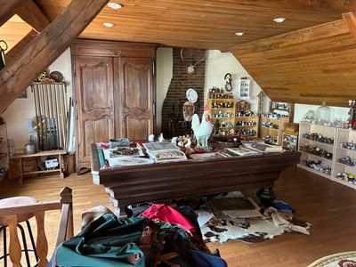 une table de billard au milieu d'une pièce où il y a plein de choses par terre