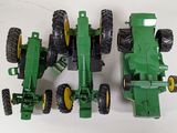 four toy tractors that are sitting on a white surface
