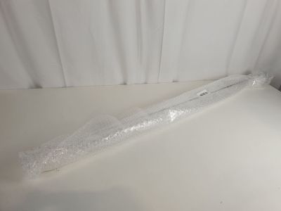un objet en plastique posé sur une table blanche, avec un rideau blanc en arrière-plan