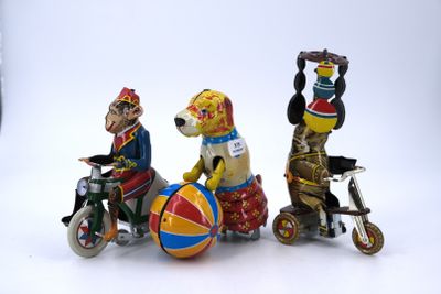 three figurines of dogs riding on tricycles