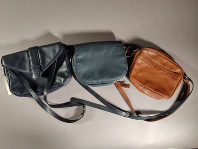 three leather purses are lined up on a white surface