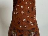 a brown vase sitting on a table with a white wall in the background