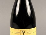 une bouteille de vin rouge avec une étiquette jaune sur fond gris