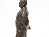 bronze statue of a man with a cane and hat on a white background