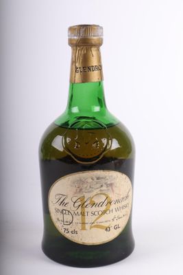 une vieille bouteille de whisky posée sur une surface blanche