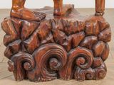 a wooden sculpture of a man sitting on a rock