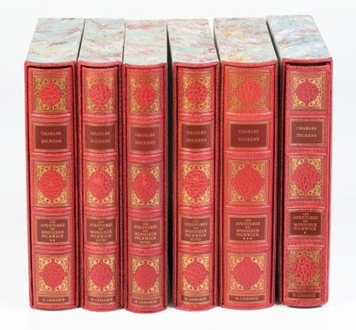 six livres rouges sont alignés sur une surface blanche
