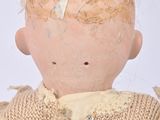 a small doll with a broken head on a white surface