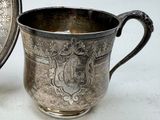 a silver cup sitting next to a plate on a table