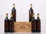 quatre bouteilles de vin sont alignées devant une caisse en bois