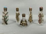 six petites bouteilles dont le verre est de différentes couleurs et ornées de décorations métalliques