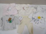 Plusieurs vêtements pour bébé sont disposés sur une surface blanche