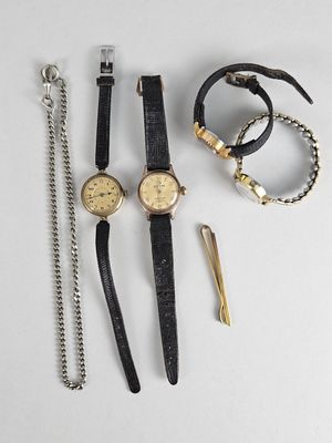 trois montres et une paire de ciseaux sont posés sur une table
