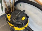 yellow and black vacuum sitting on the floor next to a potted plant
