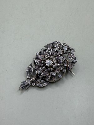 a silver brooch that has a bunch of flowers on it