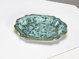 une assiette verte et dorée posée sur un fond blanc