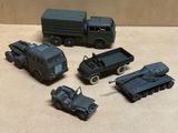 cinq véhicules militaires miniatures et un camion posés sur une table