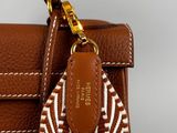 the brown and white bag has a leather handle with a gold clasp