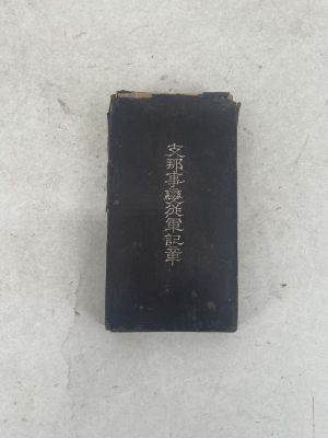 an old black book with writing on it sitting on a white surface