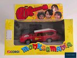 a red toy car in a yellow box with a picture of the beatles