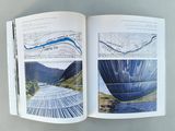 an open book with a picture of a lake and mountains