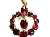 a close up of a pendant with red stones on a white background