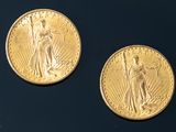 two gold coins sitting side by side on a black surface
