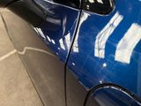 a blue car parked in a parking lot with its door open
