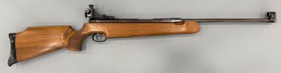 un fusil accroché au mur d'une pièce aux murs blancs